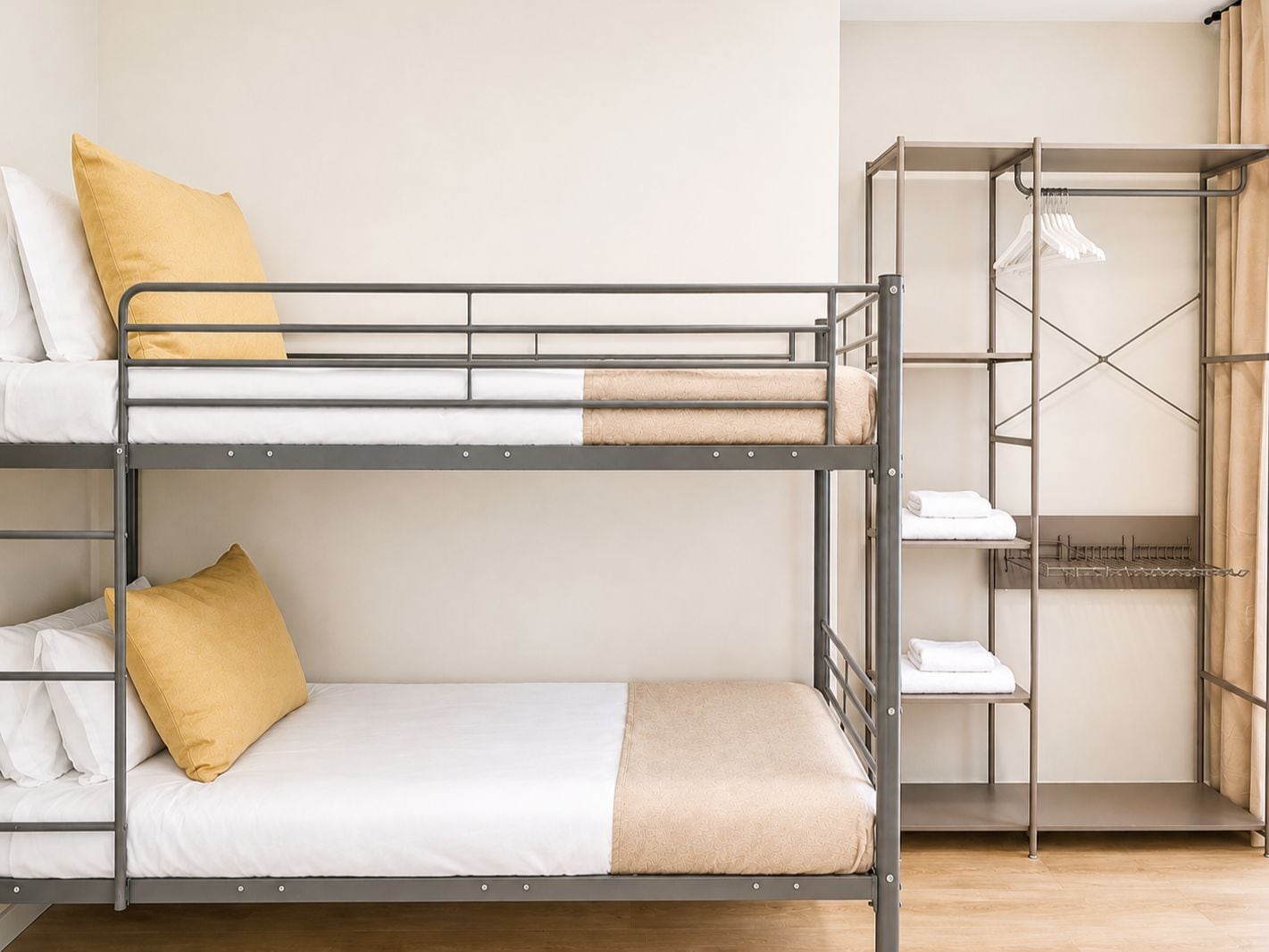 A bunk bed room with a metal frame, white bedding, and a beige throw blanket.