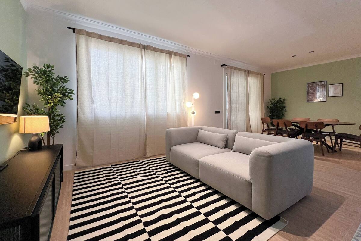 Una sala de estar con un sofá, una mesa de comedor con sillas, una lámpara y un tapete a rayas.