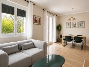 Een moderne woonkamer met een bank, een eettafel met stoelen en een glazen salontafel.