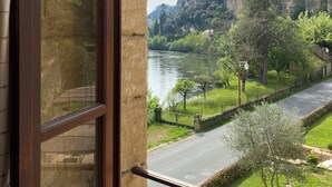 A view from a window overlooking a river, a road, and a mountainous landscape.