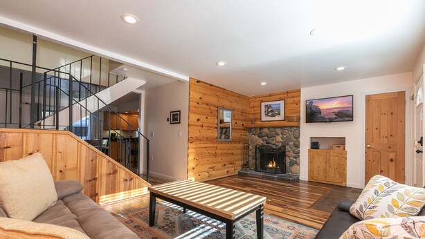 A spacious living room with a wooden staircase, a fireplace, and a cozy seating area. - Trailside Tahoe Townhouse (Tahoe city)