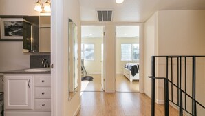 A hallway with a bathroom on the left, a staircase on the right, and a bedroom at the end. - Trailside Tahoe Townhouse (Tahoe city)