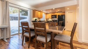 A spacious kitchen with wooden cabinets, a large dining table, and a refrigerator. - Trailside Tahoe Townhouse (Tahoe city)