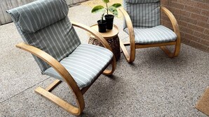 Zwei gestreifte Stühle mit Holzrahmen und ein kleiner Tisch mit einer Blumentopf-Pflanze.