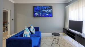 Una sala de estar con un sofá azul, un televisor de pantalla plana y un cuadro en la pared.