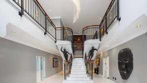 Una imponente escalera de mármol con barandillas de metal negro y un candelabro.