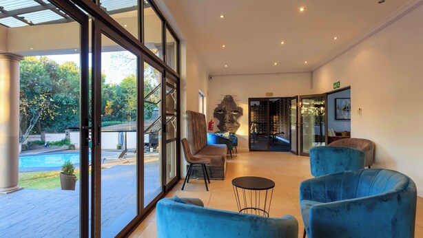 Un vestíbulo amplio con ventanas grandes, piscina y asientos tapizados en azul.
