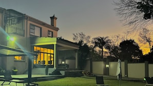 Zona de piscina residencial con una casa al fondo.