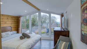Un dormitorio con una ventana grande, una cama, un escritorio y una silla.