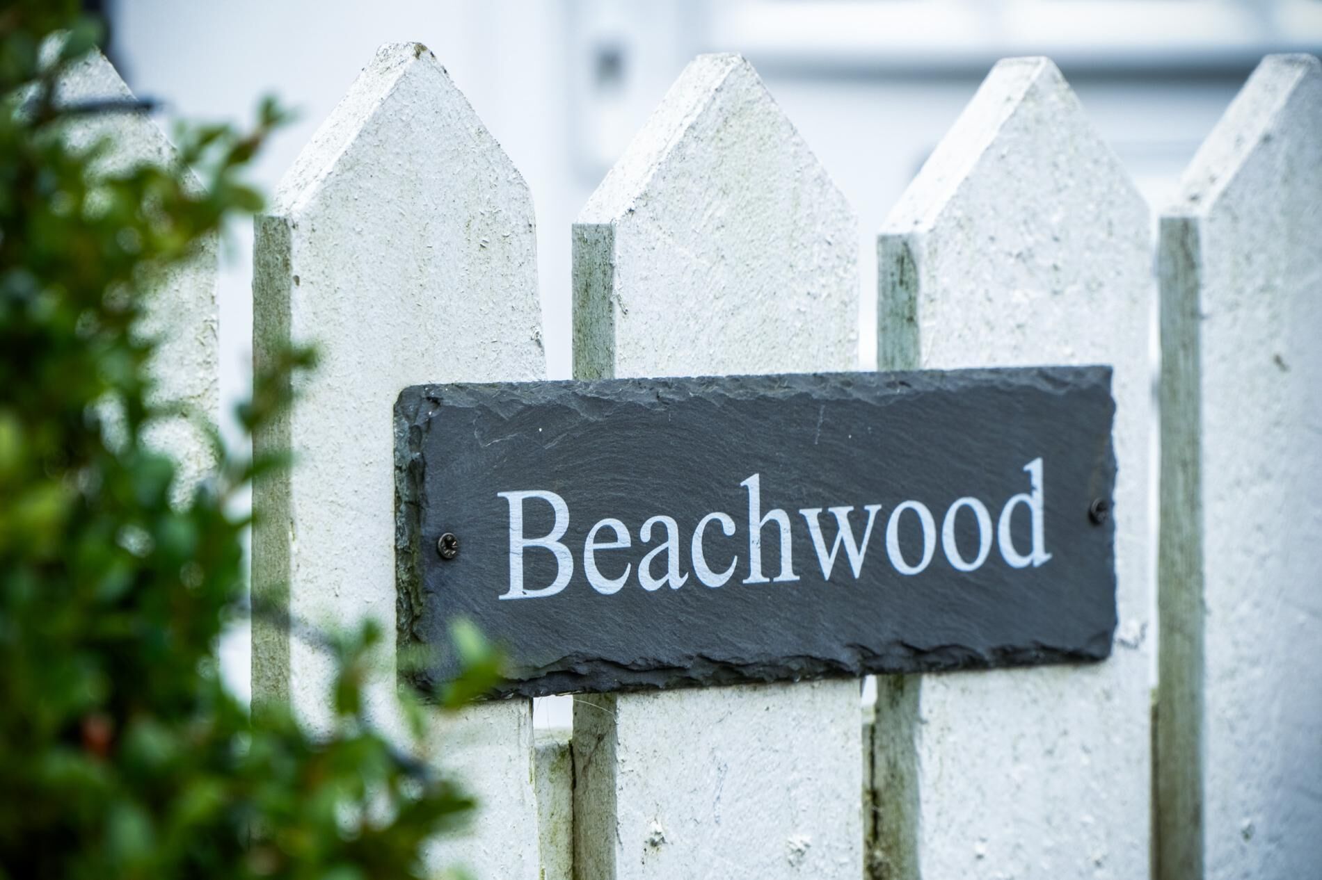 Une pancarte sur une clôture blanche en bois, sur laquelle on peut lire « Beachwood ».