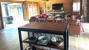 A spacious living area with a wooden ceiling, a large dining table, leather sofas, and a television mounted on the wall. - Lakeside Abode at Taylor Bay | Lake Eildon (Taylor Bay)