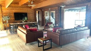 A spacious living area with a wooden ceiling, leather sofas, a dining table, and a television. - Lakeside Abode at Taylor Bay | Lake Eildon (Taylor Bay)