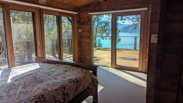 A bedroom with a bed, large windows, and a view of a lake. - Lakeside Abode at Taylor Bay | Lake Eildon (Taylor Bay)