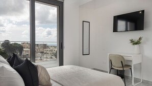 A modern bedroom with a large bed, a desk, and a TV. - Phaedrus Living: Paphos Noir Residence (Paphos)