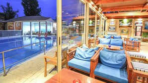 A poolside area with wooden furniture and glass doors leading to a pool.