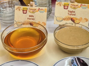 A table with two bowls of honey and tahini, each labeled with a sign. - Green Village (Xylokastro-Evrostina)