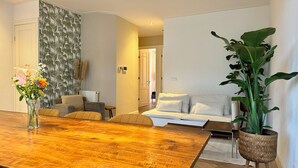 A modern living room with a wooden dining table, a sofa set, and a large potted plant.