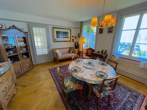 A dining area with a round table set for four, surrounded by wooden chairs.