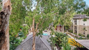 A view of a hotel with a swimming pool, surrounded by lush greenery and trees.