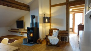 A cozy living room with a fireplace, wooden beams, a television, and a lamp. - Apartment in Stans near Wolfsklamm River (Stans)