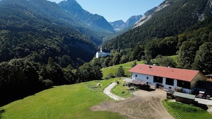 A rural mountain landscape with a white building with a red roof, surrounded by lush greenery and mountains. - Apartment in Stans near Wolfsklamm River (Stans)