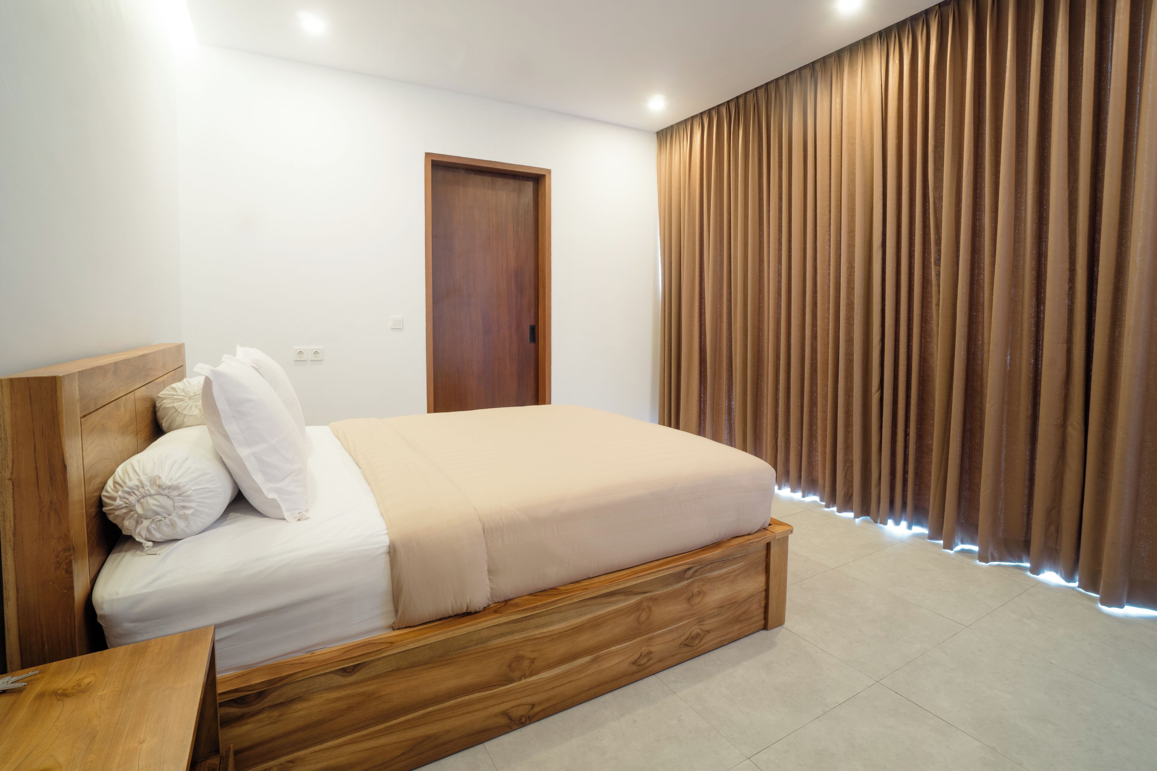 A bedroom with a wooden bed frame, a white mattress, and a wooden headboard.