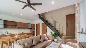 A modern living room with a sofa, coffee table, and a staircase leading to an upper level. - Sanur Bali Villas by Premier Hospitality Asia (Denpasar)