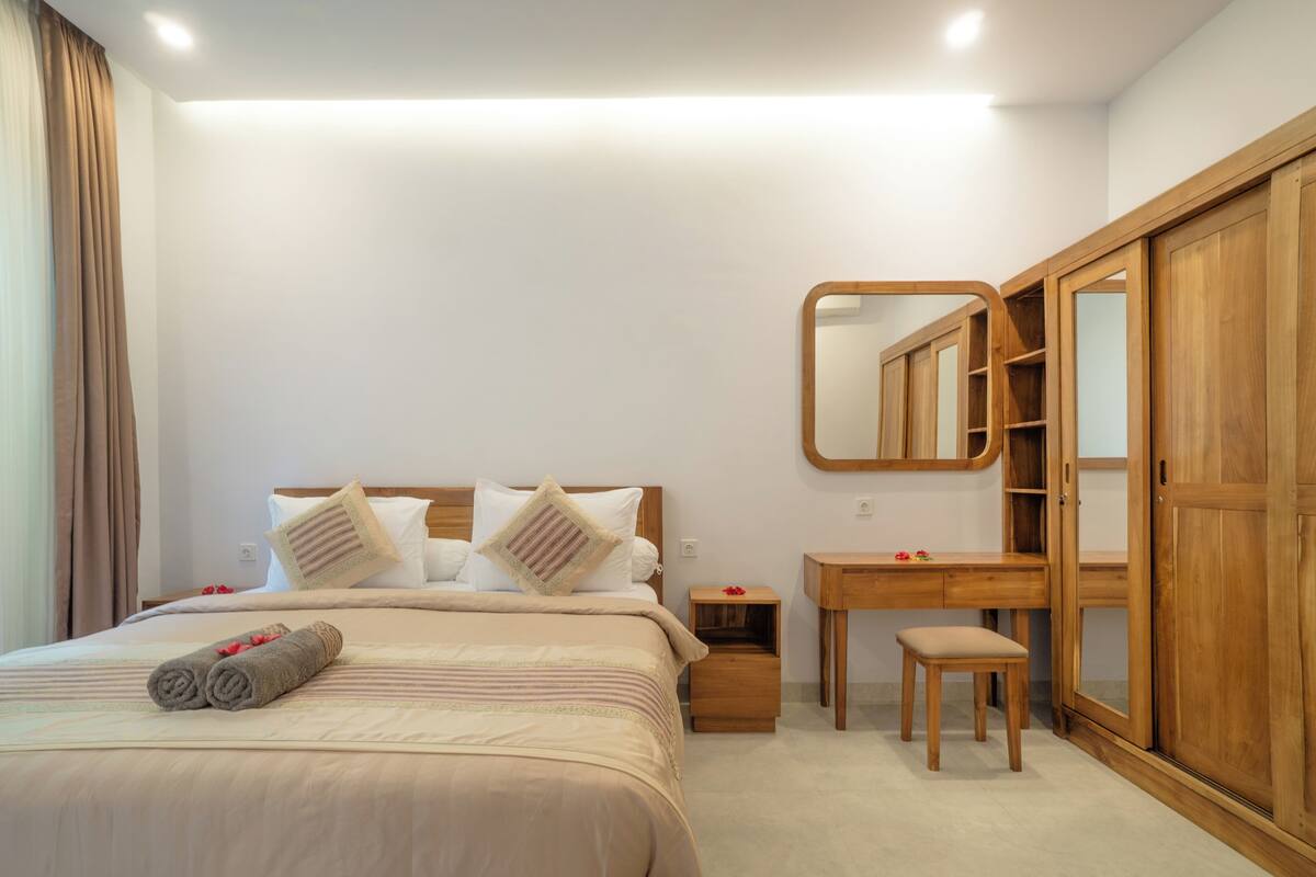 Une chambre à coucher comprenant un lit, une table de chevet, un bureau, une chaise et une armoire.