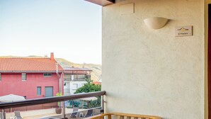 Un balcon avec une piscine, une chaise en bois, une petite table et une lampe.