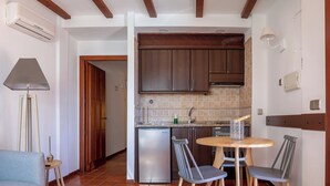 Une cuisine compacte équipée d’un réfrigérateur, d’un évier et d’un coin repas avec des chaises et une table.