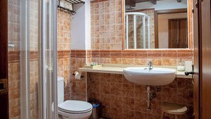 Une salle de bain équipée d’une douche, de toilettes, d’un lavabo et d’un miroir.