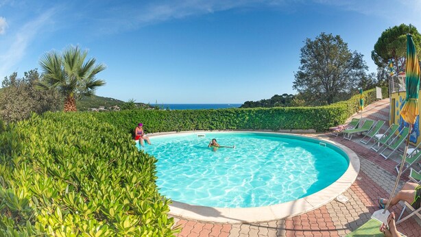 A swimming pool with clear blue water, surrounded by lush greenery and a paved deck with lounge chairs. - Appartements mit Veranda, Andora (ANDORA (SAVONA))
