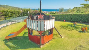 A playground with a slide and climbing structure, surrounded by grass and a view of the sea. - Appartements mit Veranda, Andora (ANDORA (SAVONA))
