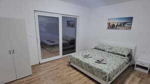 Ein Schlafzimmer mit Bett, Kleiderschrank und einer Schiebetür, die auf einen Balkon führt.