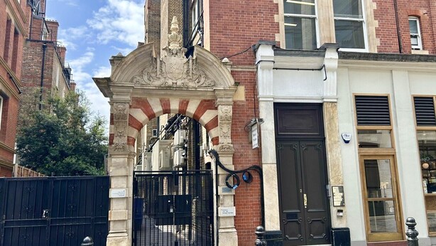 Un edifici amb una porta negra, una porta blanca i una façana de maó.