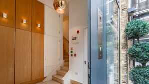 Un interior moderno con paneles de madera, una escalera y una puerta de cristal que da al exterior.