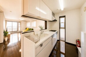 A modern kitchen with white cabinetry, a stainless steel range hood, and a gas stove. - yuuga (Tokyo)