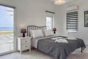 Una camera da letto con un letto, comodini, una finestra con persiane e vista mare.