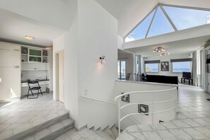 Un ambiente spazioso con una scala che conduce a un balcone, una zona cucina e un'area salotto con vista.