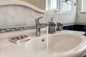 A bathroom with a white sink, a modern faucet, and a decorative soap dispenser.