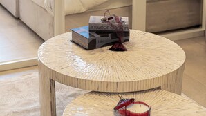 Ein Schlafzimmer mit einem Bett, zwei runden Holztischen und einer auf einem Tisch stehenden Kiste mit der Aufschrift 'Interior Design'.