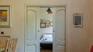 Una habitación con una cama, una silla de madera, una mesa de comedor y un sofá.