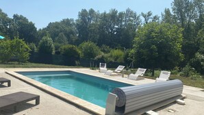 A rectangular swimming pool with a tiled edge, surrounded by a concrete deck. There are several lounge chairs and a small table near the pool. - Charming single-storey house with saltwater pool. Completely renovated in 2022 (Espéraza)