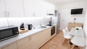 Une cuisine moderne avec des meubles blancs, un four à micro-ondes, une machine à café et un évier.