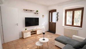 Un salon avec un téléviseur, un canapé, une petite table et un radiateur.