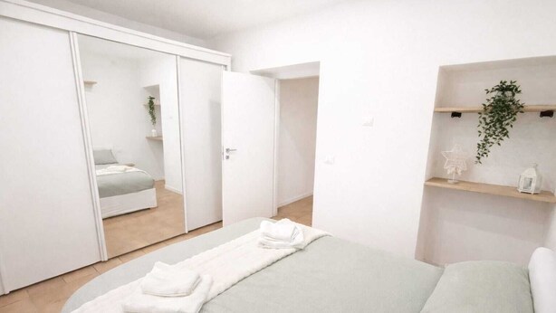 Une chambre à coucher moderne avec un lit, une armoire et une étagère ornée d’une plante.