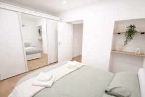 Une chambre à coucher moderne avec un lit, une armoire et une étagère ornée d’une plante.