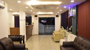 A hotel lobby with a reception desk, sofas, a foosball table, and a TV screen. - Rihan Goa Holiday Homes (Calangute)