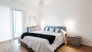A bedroom with a bed, bedside tables, a nightstand, a door, and a ceiling light fixture. - Cozy JOIVY Suite 3 with parking (Como)