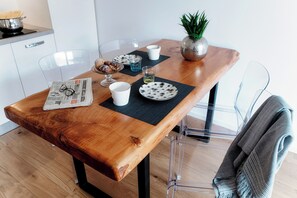 A wooden dining table with clear glass chairs, a newspaper, a bowl of pastries, a glass of water, and a small plant. - Cozy JOIVY Suite 3 with parking (Como)